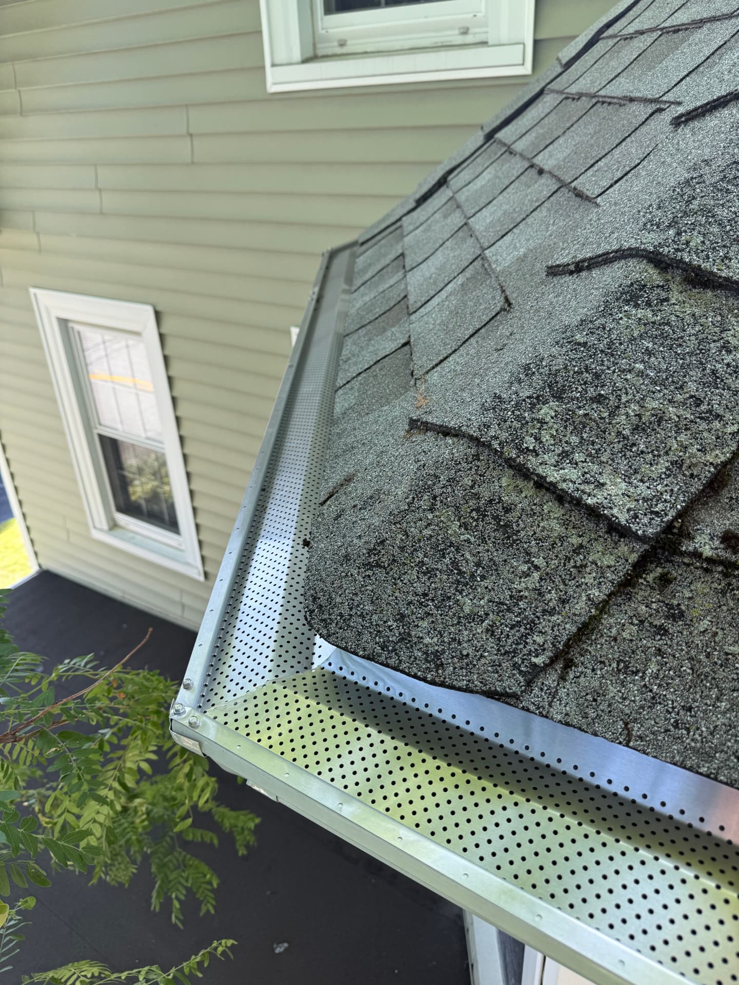 New perforated metal gutter guards installed on a residential roof